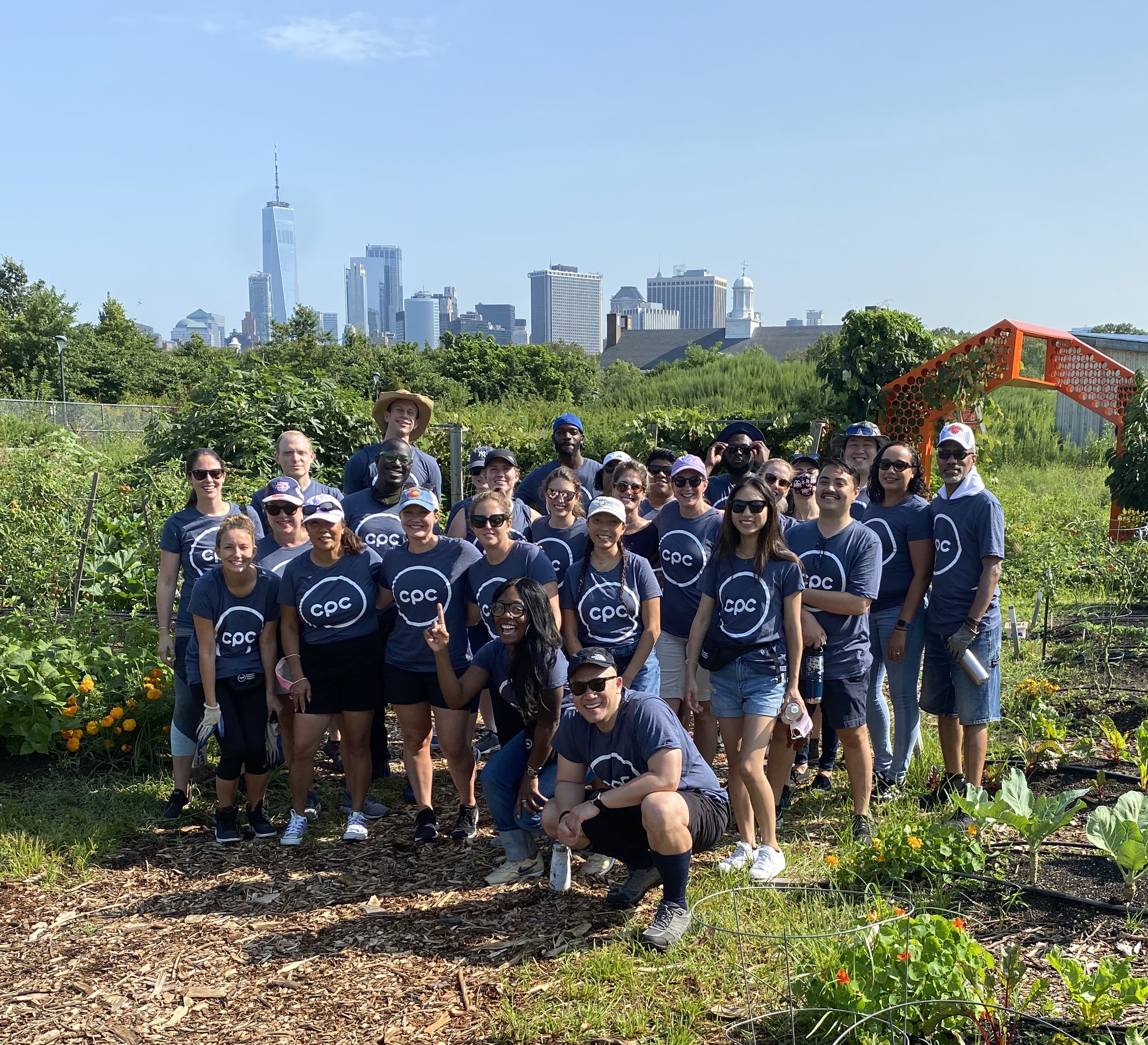 Group of people smile in urban farm wearing CPC shirts.