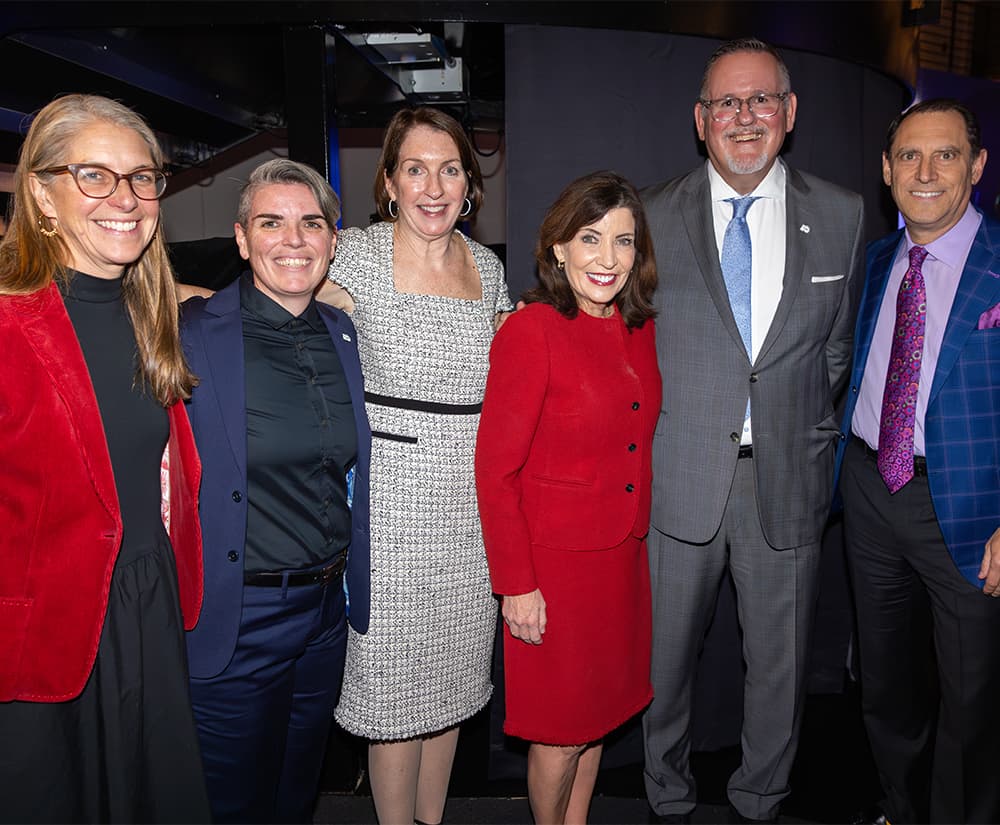 Six people standing and smiling looking into camera.