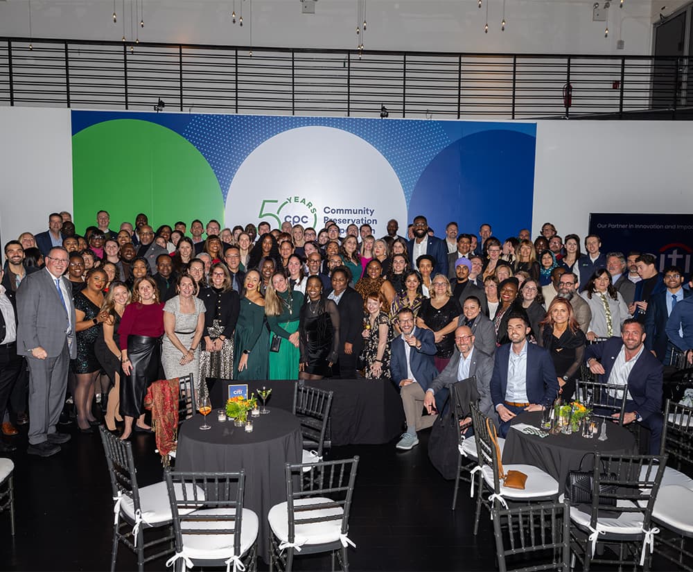 Roughly 100 event attendees posing and smiling in front of CPC 50 years logo backdrop.